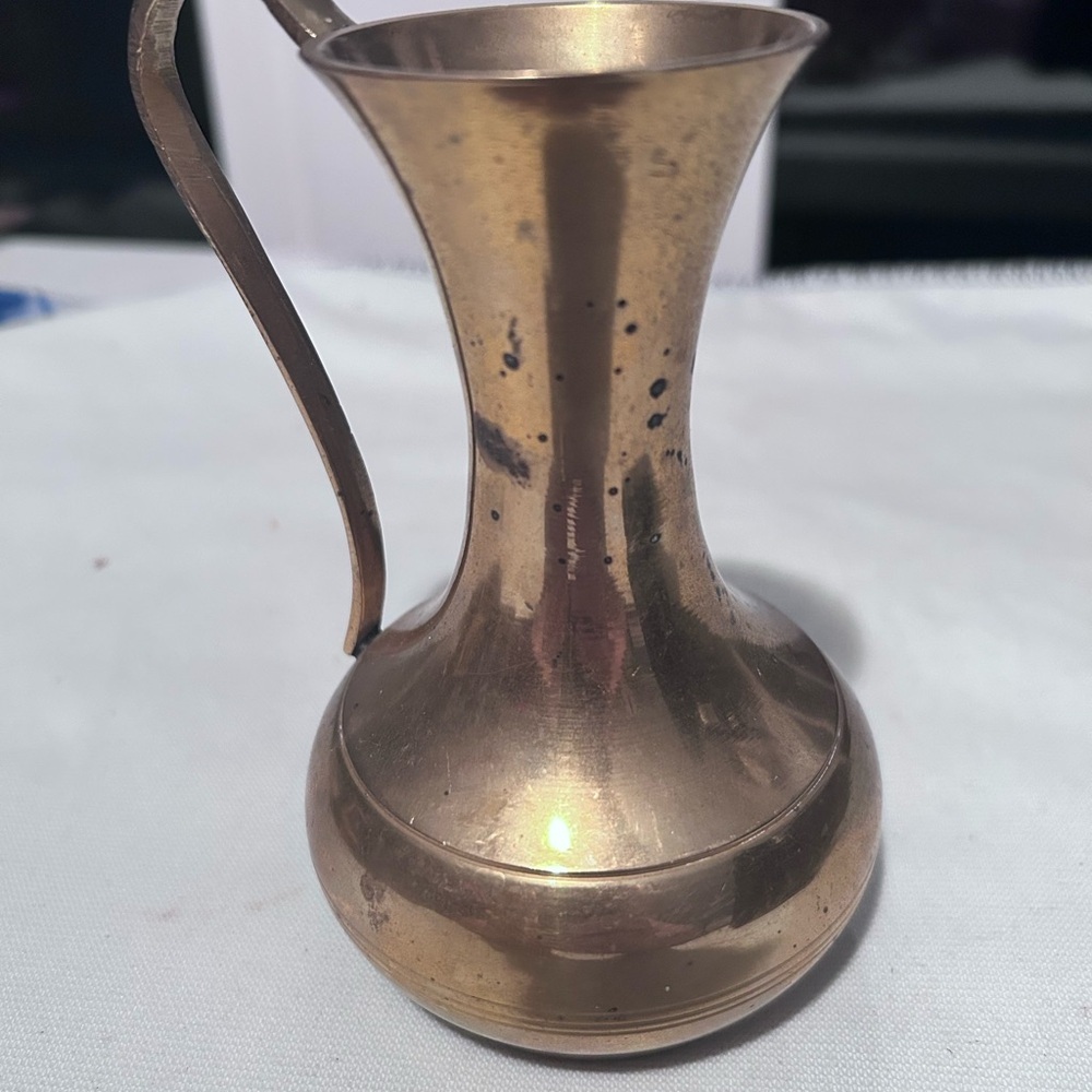 A  small vintage Indian brass decorative pitcher with a curved handle.- preloved